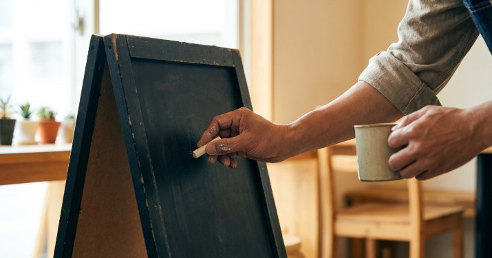 黒板タイプのA型看板にチョークで書き込む様子