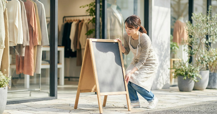 看板を持ち運んで設置場所を確認する店舗スタッフ